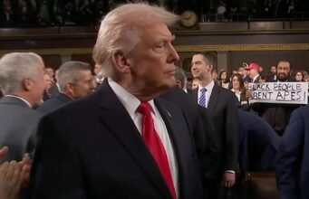 Al Green segura uma placa dizendo “Negros não são macacos” atrás de Donald Trump no discurso sobre o Estado da União