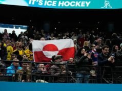 Torcedores levantam a bandeira da Groenlândia em protesto contra a vitória olímpica dos EUA no hóquei sobre a Dinamarca