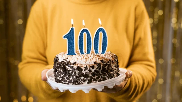 woman-holding-birthday-cake-for-100-year-old.webp.webp